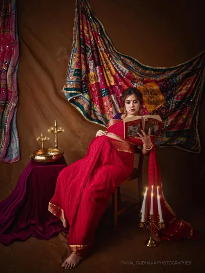 The subject is posed reading a book, suggesting a quiet moment of reflection and wisdom. The scene is lit to resemble the soft, directional light seen in many of Varma's paintings.