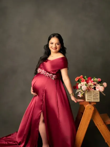 A sweet and stylish shot in our burgundy satin gown, accessorized with a floral belt and props for a personalized touch.