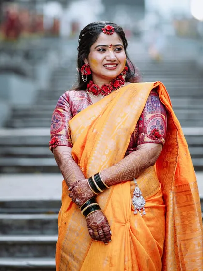 The bride smiling during her Haldi ceremony, set against a backdrop of stairs.