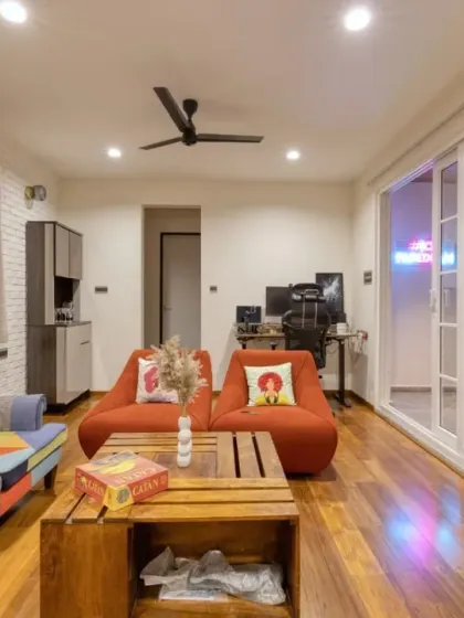 The multipurpose room at Villa 17, connected to the terrace. It features a colorful patchwork sofa and comfortable orange armchairs, perfect for relaxing.