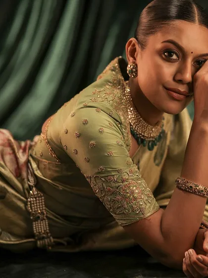 A model in a soft green floral saree, paired with a matching green blouse. The blouse features delicate embroidery on the sleeves, complementing the saree's print.