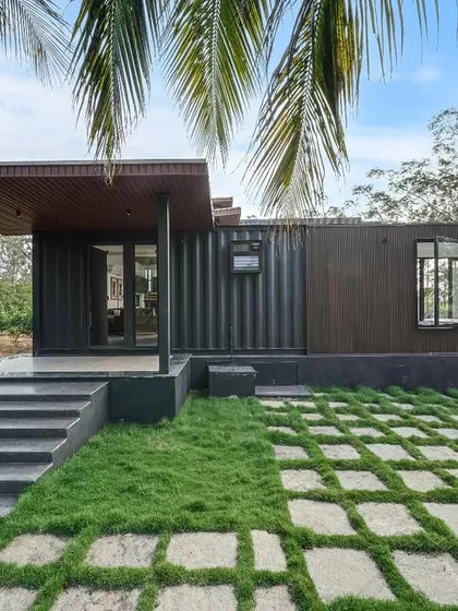 This project showcases how a modern prefab home can blend perfectly with nature. The combination of dark corrugated steel and warm wood-panel cladding creates a sophisticated look, while the large glass doors connect the indoor space with the surrounding landscape.