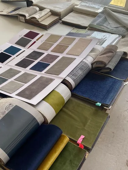A sea of possibilities. Selecting the perfect fabrics is a crucial step in our process. Here, we are exploring a range of velvets, linens, and textured weaves in various colors to find the exact right fit for a project.