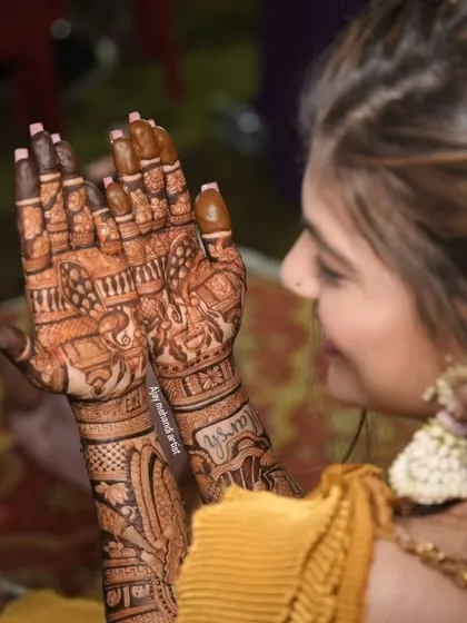 A candid shot of a client admiring her detailed bridal mehndi, which includes elephant and floral motifs.