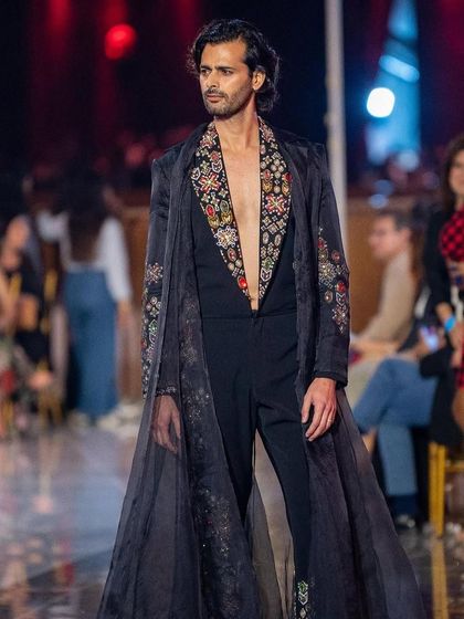 A profile view of the male grooming for the fashion show, highlighting a strong jawline and clean skin finish that stands up to the harsh runway lighting.