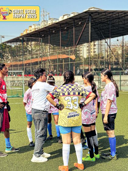 A coach gives tactical instructions to the girls' team during a huddle. Strategic thinking is a key part of our curriculum.