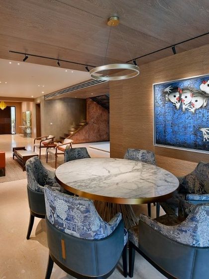 The dining area in a renovated Delhi home, where a playful piece of art overlooks a modern marble-topped table. This space flows into the living area, reflecting our approach of breaking down walls to create open, connected interiors.