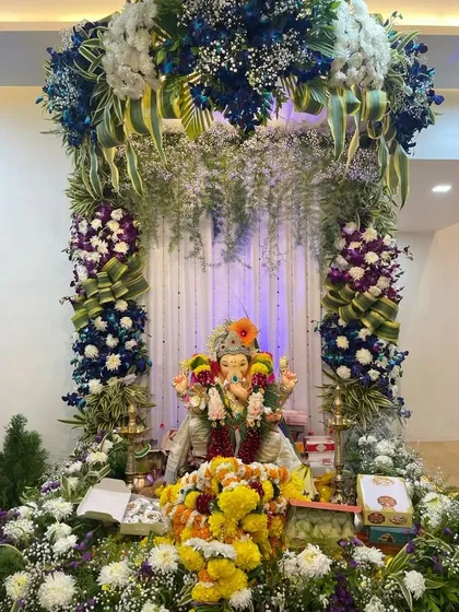 This luxurious Ganpati decoration showcases a unique color palette of deep blues, purples, and whites. We used premium flowers and cascading greens to build a grand and royal canopy, demonstrating our ability to work with unconventional themes.