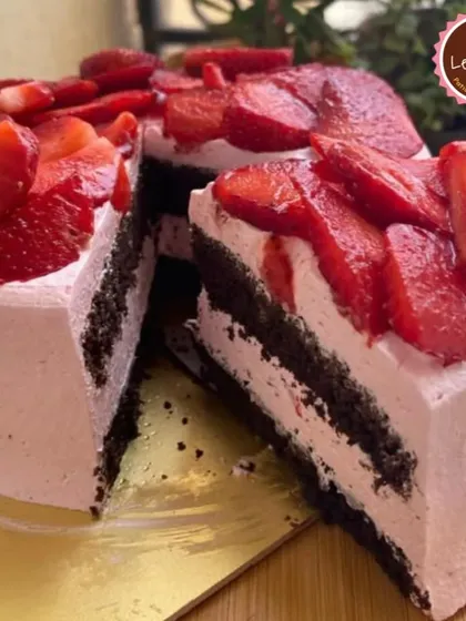 A slice of my Chocolate Strawberry Mousse Cake, showing the distinct layers of dark chocolate cake and light pink strawberry mousse, topped with plenty of fresh strawberries.