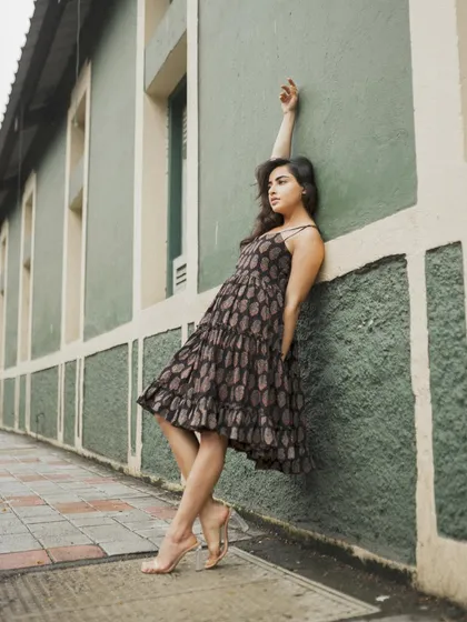 A similar pose to the previous shot but with a wider frame, showing more of the architectural background.