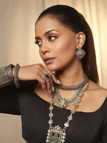 A beautifully composed shot that highlights both the layered necklaces and the model's elegant pose. Her makeup enhances her bone structure and adds to the overall sophisticated vibe.
