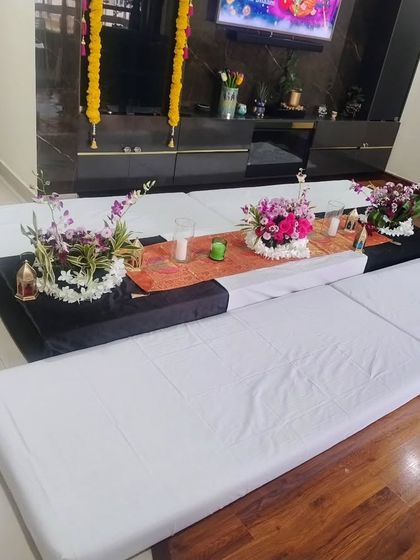 A low seating arrangement with mattresses and a floral table runner for a traditional meal or ceremony.