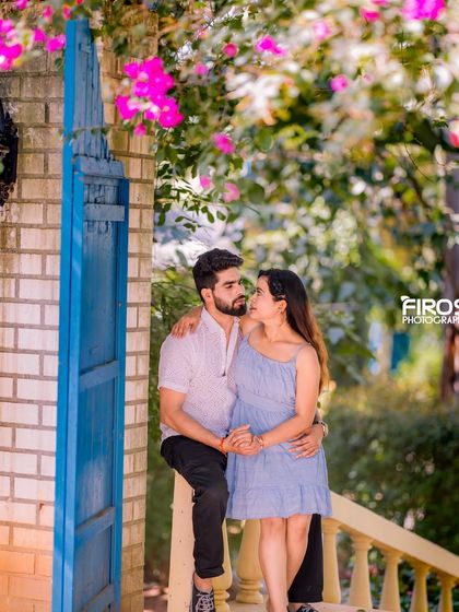 A romantic couple poses on a bridge with a blue gate and blooming flowers, part of our charming European-style sets.