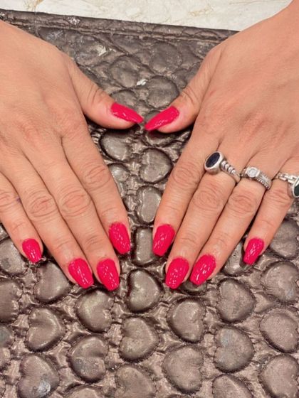 A vibrant set of hot pink almond nails. This glossy, eye-catching color is perfect for anyone who loves a bold manicure.