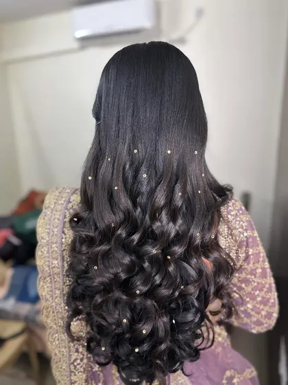 A simple yet stunning reception look. The hair is styled in open curls, decorated with small pearl accessories scattered throughout for a touch of sparkle.