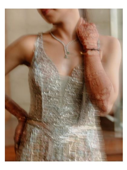 An artistic, motion-blur portrait of the bride. This abstract shot focuses on the texture and shimmer of her gown, with a hint of her hennaed hand, creating a dreamy and impressionistic feel.