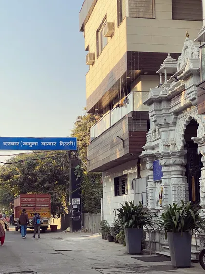 A street view near Yamuna Bazar, showing the mix of modern buildings and traditional temples that define Delhi's landscape.