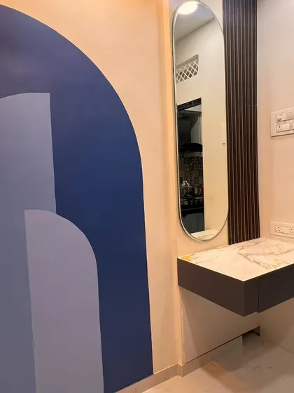 A stylish vanity or console area with a unique geometric wall paint design and an elegant oval mirror.