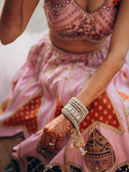 A close-up on the bride's hands, showcasing her intricate mehndi and beautiful bangles. These detail shots are an important part of the wedding album.
