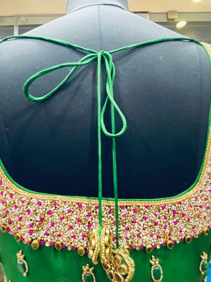 For a truly grand look, I do full-coverage bead and stone work. This green bridal blouse has a heavy, hand-embroidered back with thousands of beads, all stitched securely for a perfect finish. The matching latkans complete the design.