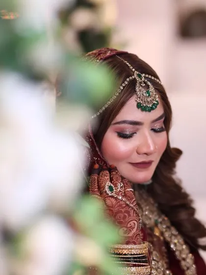 A beautiful shot through the flowers, capturing the bride's gentle smile. Her makeup is flawless, with glowing skin and eyes that sparkle.