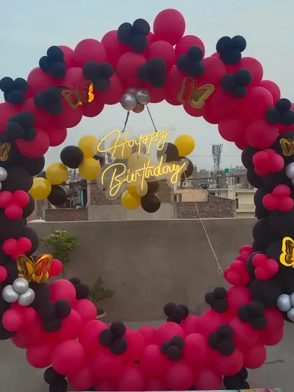 A striking red and black balloon ring for a rooftop birthday party. The butterfly accents add a touch of elegance to the bold color combination.