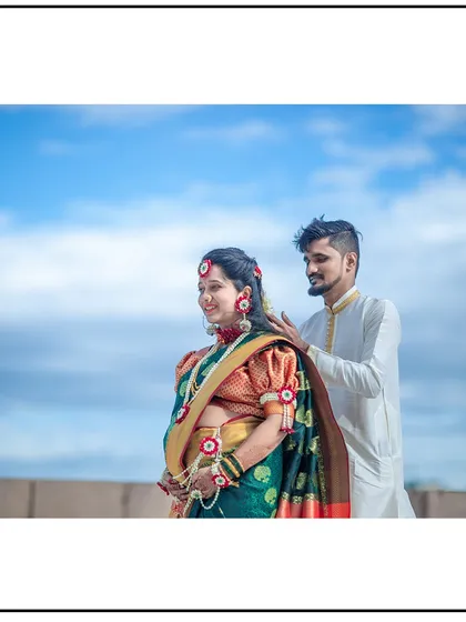 A beautiful portrait of a couple in traditional attire, set against a bright blue sky.