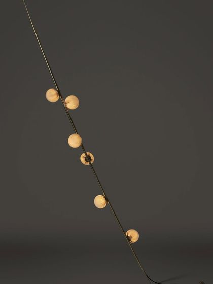 A studio shot of a single Bocci 84 stem, emphasizing its minimalist form and the warm glow of the individual glass spheres.