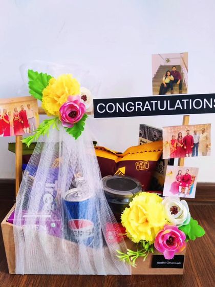 A simple and elegant congratulations hamper that's also budget-friendly. It's decorated with flowers and personal photos, and filled with a selection of snacks and a drink to celebrate their success.