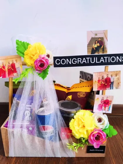 A simple and elegant congratulations hamper that's also budget-friendly. It's decorated with flowers and personal photos, and filled with a selection of snacks and a drink to celebrate their success.
