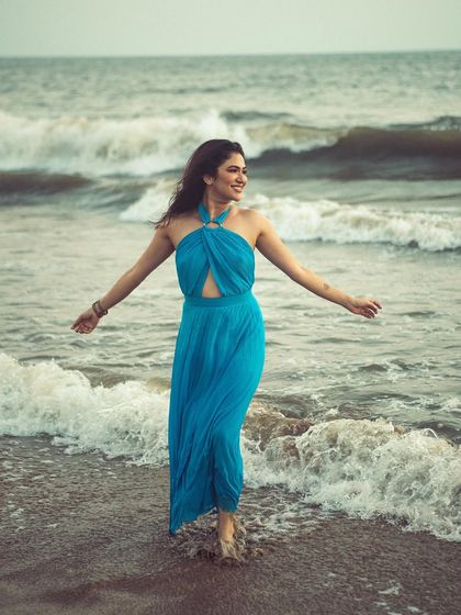 A model enjoys the waves in a beautiful blue dress. This shot captures pure joy and movement, perfect for a lifestyle or travel-themed shoot.