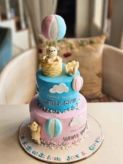 A sweet "Twinkle Twinkle Little Star" gender reveal cake in pastel pink and blue, featuring teddy bears in a hot air balloon.