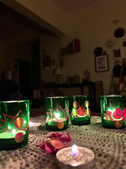 A set of green glass candle holders painted with elegant lotus flowers.