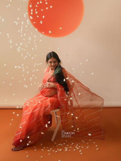 Seated with a gentle smile, she looks down at her bump. This quiet, contemplative pose is perfect for capturing the personal connection between a mother and her unborn child.