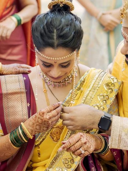 A close-up of a Maharashtrian wedding ritual, where the groom places the ring on the bride's finger. This detail shot highlights the cultural richness and personal significance of the ceremony.