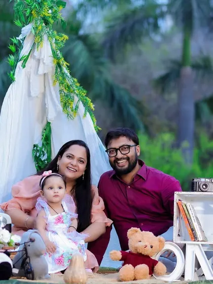 A beautiful family portrait from an outdoor cake smash session. The picnic-style setup with a teepee and props creates a charming scene for celebrating a first birthday.
