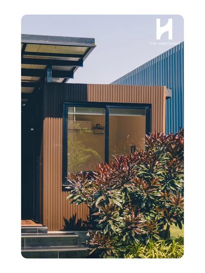 This image captures the modern aesthetic of the twin container office, with its dark window frames and clean, geometric lines against a backdrop of corrugated steel.