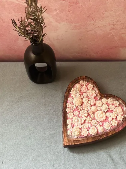 A lovely shot of my heart-shaped dough bowl candle, filled to the brim with delicate pink and white wax flowers. It's a true statement piece, perfect for adding a touch of romance and fragrance to any room.