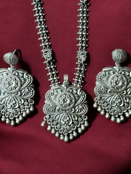 A complete statement set in oxidised silver. This matching necklace and earring set features incredibly detailed floral and leaf motifs, all crafted from pure 925 silver.