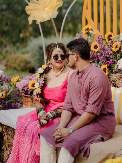 A sweet, candid moment between the bride and groom during their Haldi ceremony. The unique seating on a decorated hay bale adds a touch of rustic charm.
