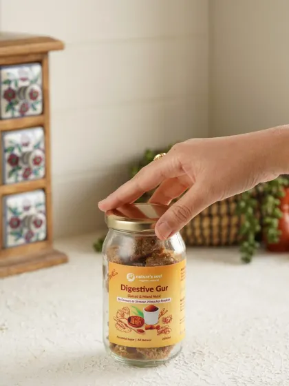 A simple, clean shot with a hand reaching for the jar of Digestive Gud, adding a human element and suggesting ease of use.