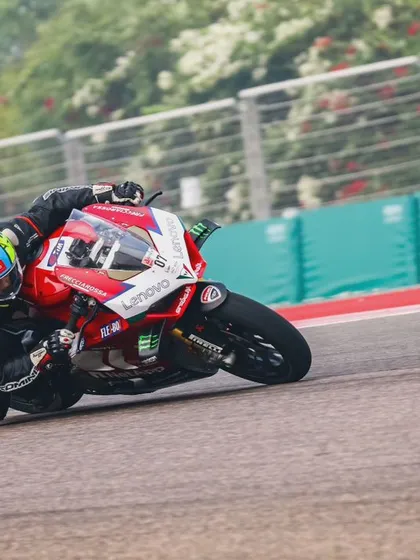 A close-up action shot of a Ducati rider fully committed to the corner, showcasing intense focus and professional riding gear.