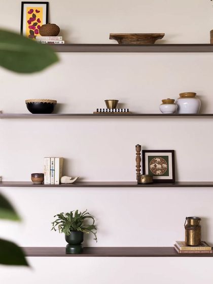 A close-up of the styled shelves, featuring a mix of traditional pickle jars, modern books, and vintage brass milk cans.