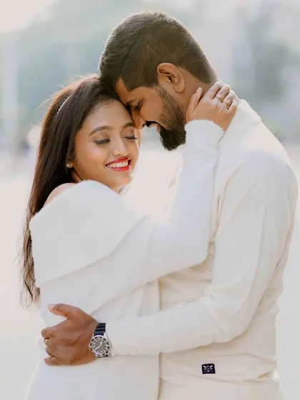 A tender moment between a couple dressed in white, captured in the warm, soft light of a city afternoon.