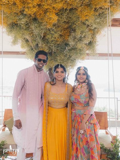 The couple posing with a guest at their Bali-themed Haldi. Our events are all about bringing family and friends together to celebrate in a beautiful, curated environment.