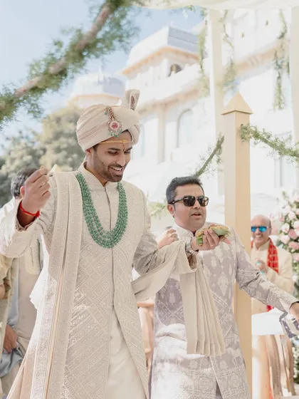 A close-up of the groom's happy expression, with the stunning emerald jewelry adding a pop of color to his traditional attire.