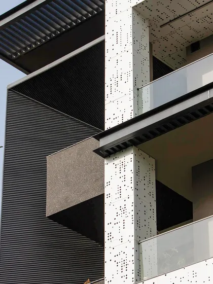 A close-up showing the contrast between the dark, fluted panels and the white, perforated jali. This juxtaposition of textures and colors is a key element of the modern design.