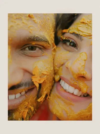 An extreme close-up of the couple's smiling faces, covered in Haldi. This shot is all about raw emotion and happiness.