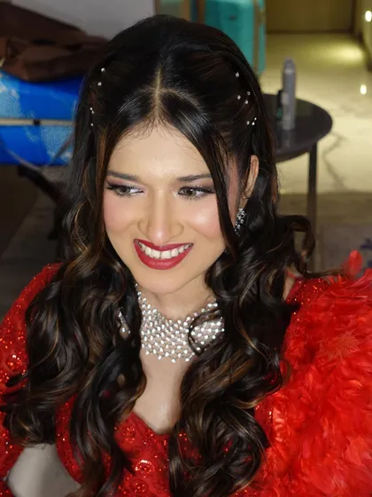 A candid shot of Amileen, her smile lighting up the frame. Her hair is styled in soft waves with pearl accessories.