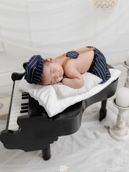 Sweet dreams on a grand piano. This creative newborn setup combines elegance and innocence, with the baby sleeping peacefully on the keys.